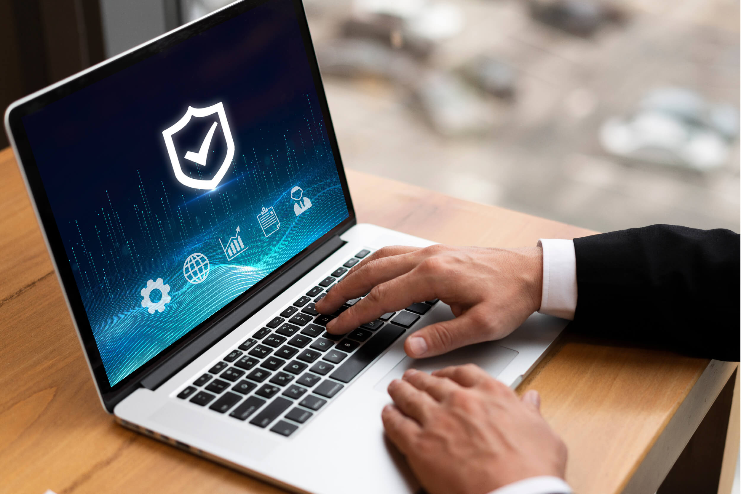 A business professional working on a laptop displaying a cybersecurity shield icon with various analytics and management symbols, representing Microsoft Copilot for Security