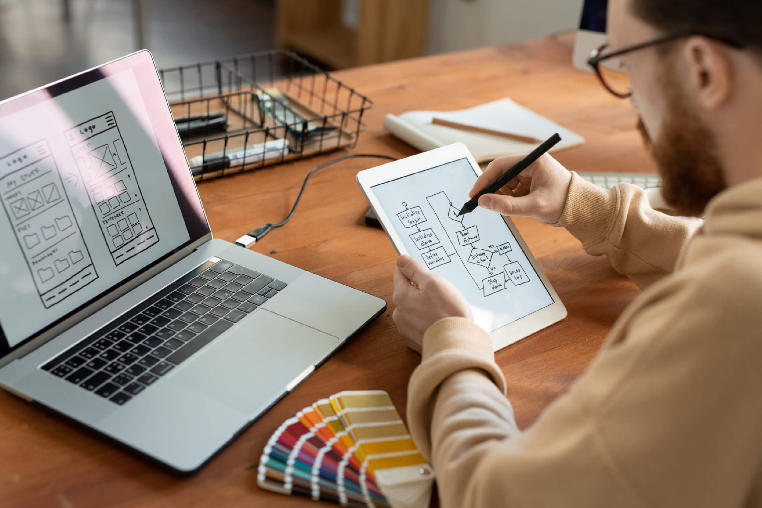 Guy working on UI UX design with a laptop and drawing, illustrating UI UX Best Practices for Improved User Retention.